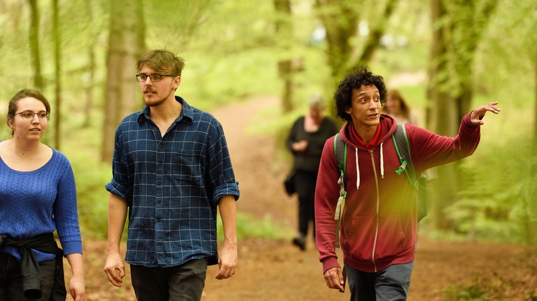 A group of friends walking along the path through Comer Woods at Dudmaston, surrounded by green trees